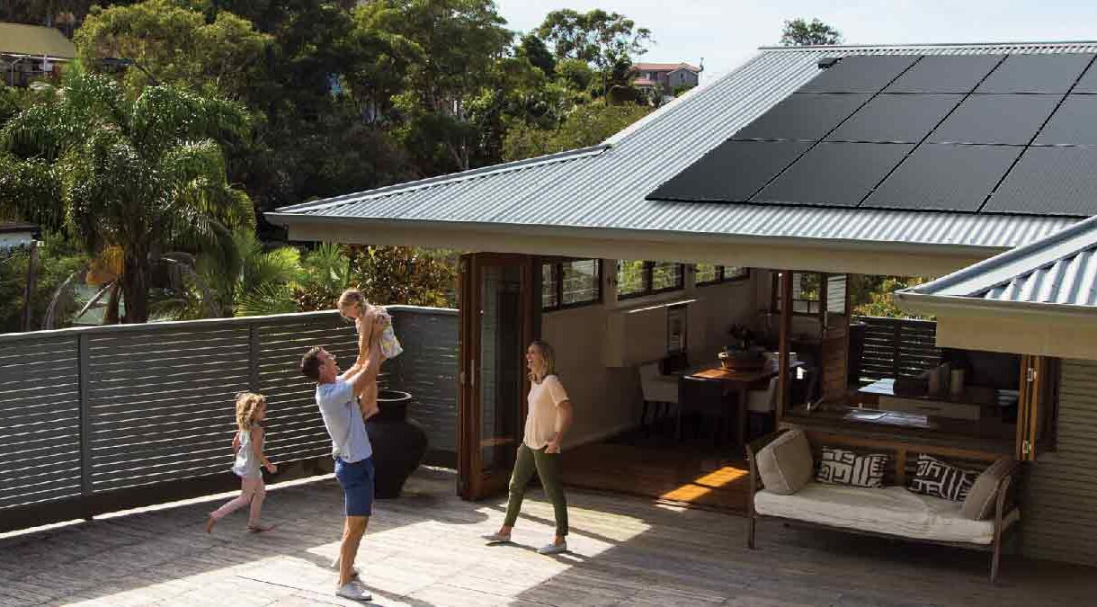Family playing in backyard of house with Solahart Silhouette solar panels on the roof