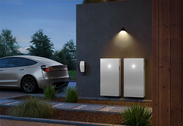 Two Tesla Powerwall 3 home battery systems installed on the outside wall of a home with a Tesla Model 3 electric vehicle nearby.