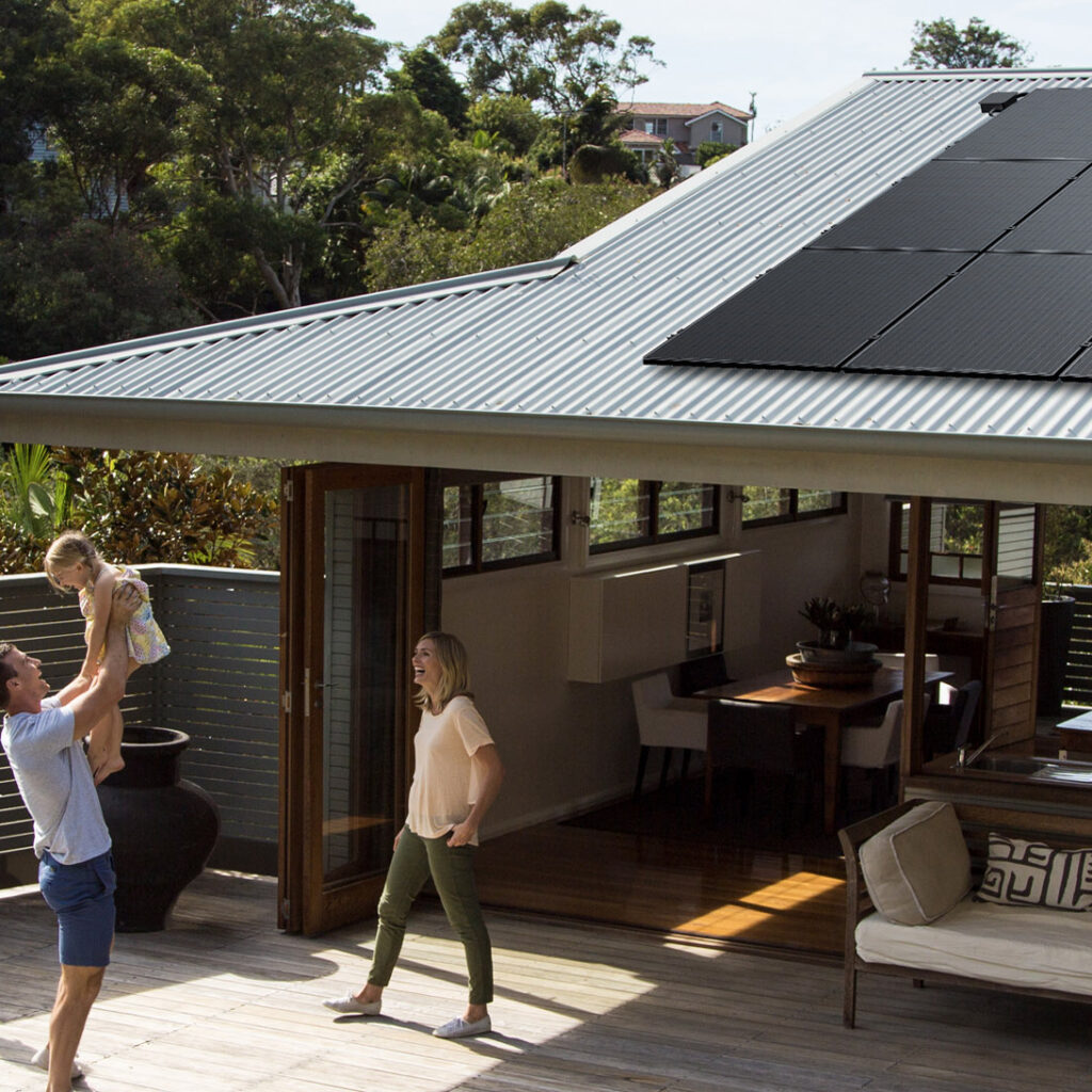 Happy family playing in their backyard with solar panels seen on the roof